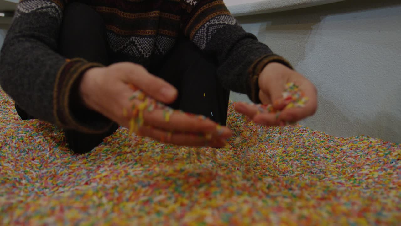 Slowmotion close up of hands digging through vibrant sprinkle pit candy texture resembling pastry toppings colorful sugar details playful dessert inspired atmosphere surreal sweet environment