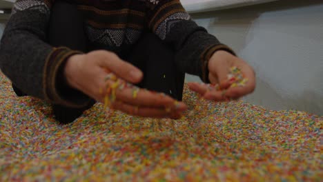 slowmotion close up of hands digging through vibrant sprinkle pit candy texture resembling pastry toppings colorful sugar details playful dessert inspired atmosphere surreal sweet environment