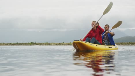 caucasian couple having a good time on a trip to the mountains, kayaking together on a lake