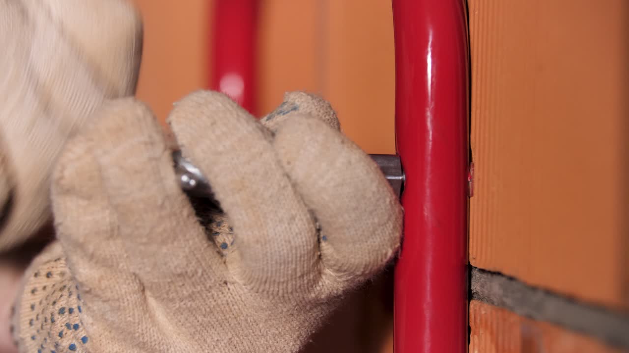 Installing a red metal handle on a brick wall
