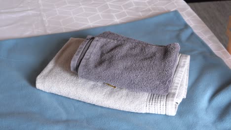 folded gray and white towels on a blue bedspread