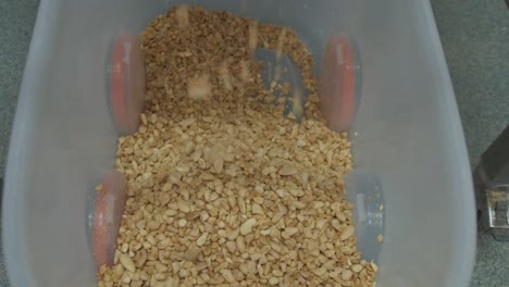 crushed almonds falling into a bin at a factory