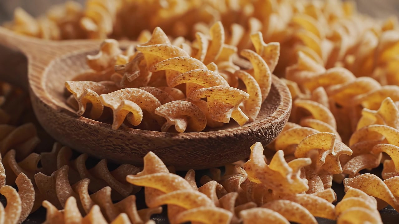 Close-up of raw whole wheat fusilli pasta in wooden spoon