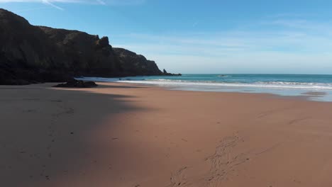 Luftaufnahme-über-Einem-Sandstrand,-Der-An-Einem-Sonnigen-Tag-Von-Wellen-Heimgesucht-Wird,-Plemont-Bay,-Jersey,-Kanalinseln