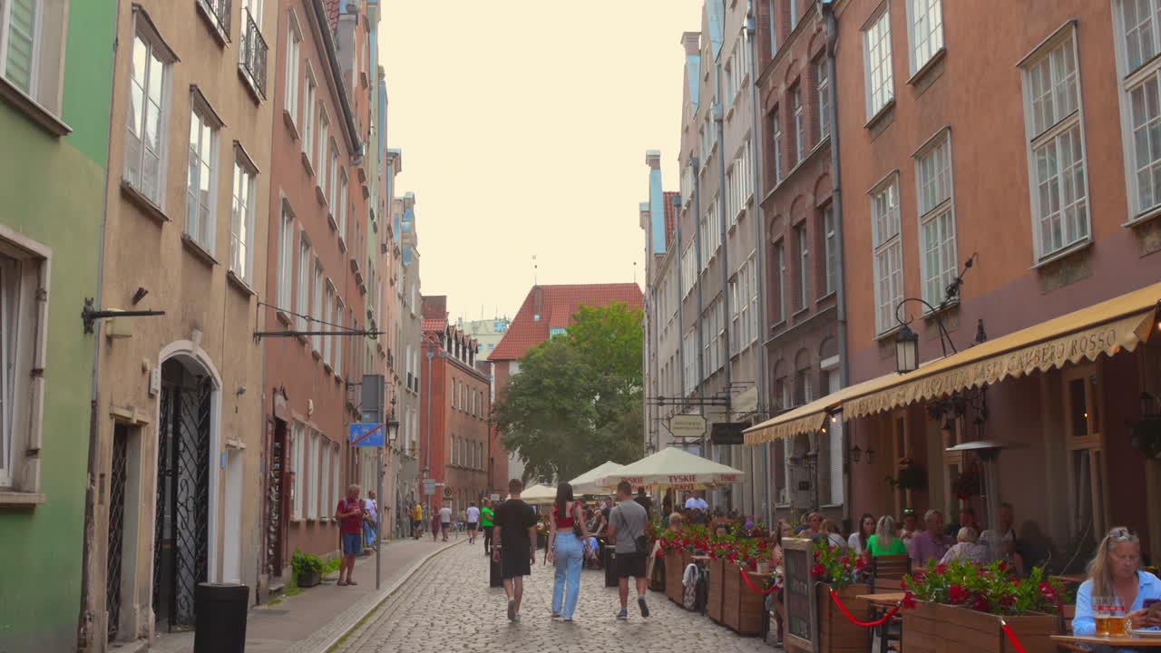 Wander through the picturesque streets of Gdansk's old town center, where colorful buildings and bustling cafes create a vibrant atmosphere during a summer evening.
