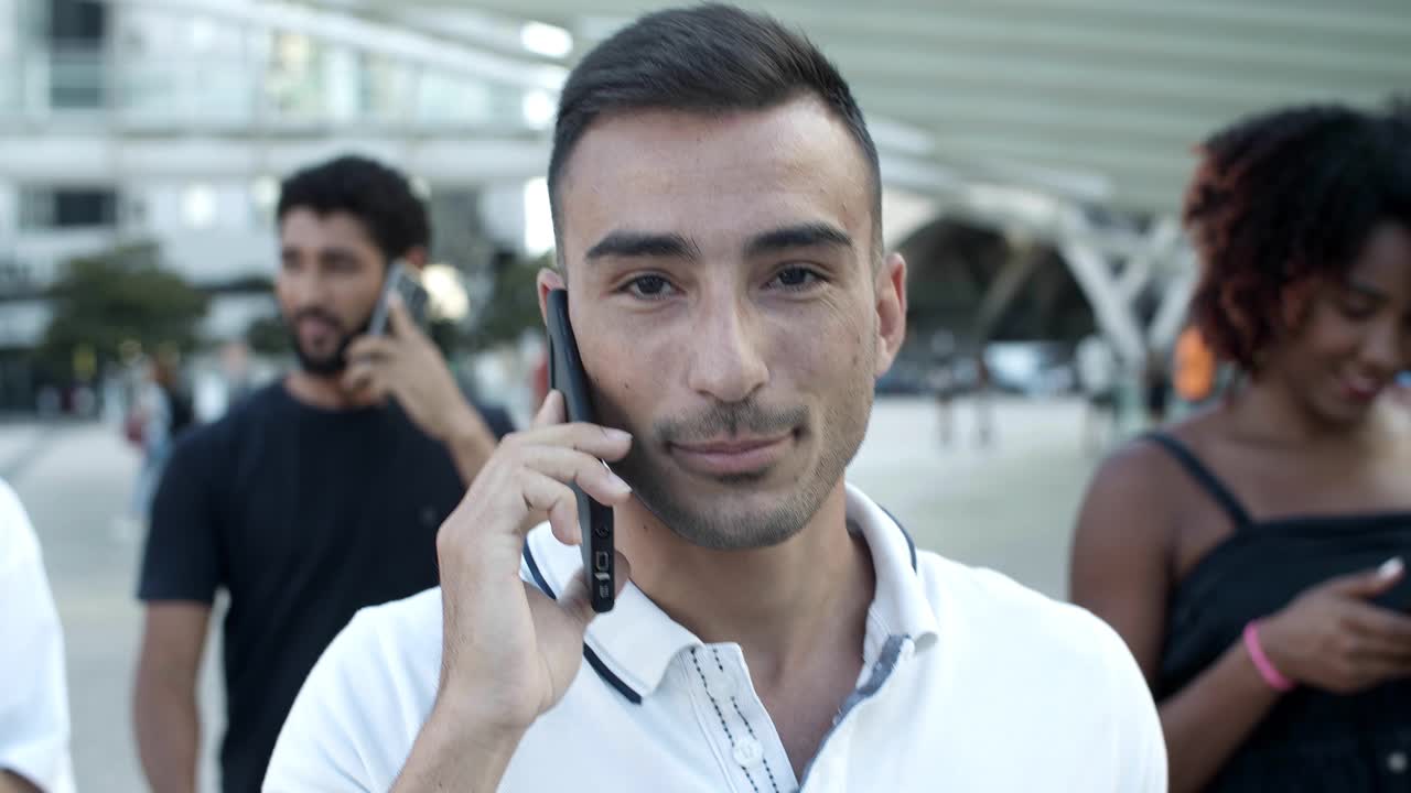 un joven sonriente hablando en un teléfono inteligente