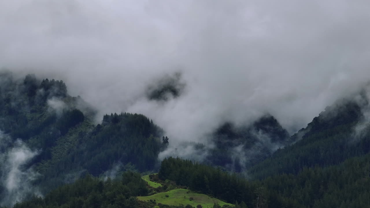 Drone Shot of Rain Clouds Moving Over Heavily Forested Mountain Range, New Zealand