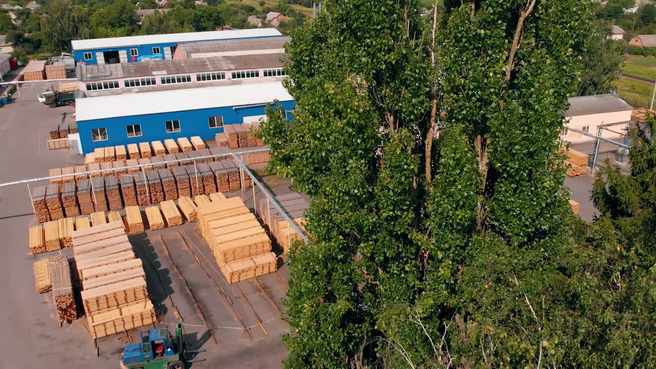 Wooden planks stored in piles at the territory of modern plant. Warehouses for storing and processing wood and manufacturing doors.