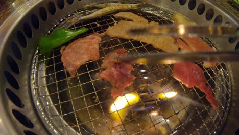 tongs flipping grilled meat on sizzling hot yakiniku japanese bbq