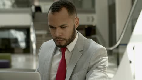 focused african american man looking at laptop