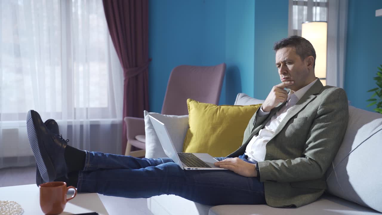Thoughtful and looking for ideas mature man working at home on laptop, texting.