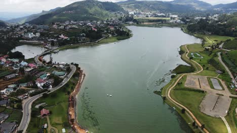 Mehrere-Boote-Und-Wasserfahrzeuge-Navigieren-Im-Blauen-Stausee-Gregory-Lake,-Während-Mehrere-Fahrzeuge-Links-Auf-Der-Kurvenreichen-Provinzstraße-Zwischen-Den-Bergen-In-Sri-Lanka-Fahren