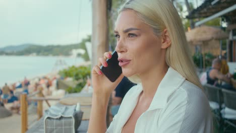 woman talking on phone at beach cafe