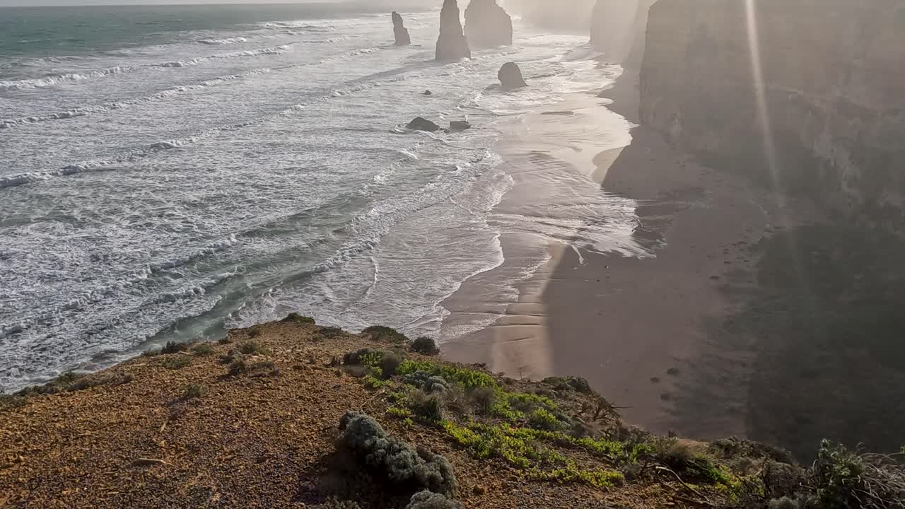 Waves crash against iconic limestone formations at sunset