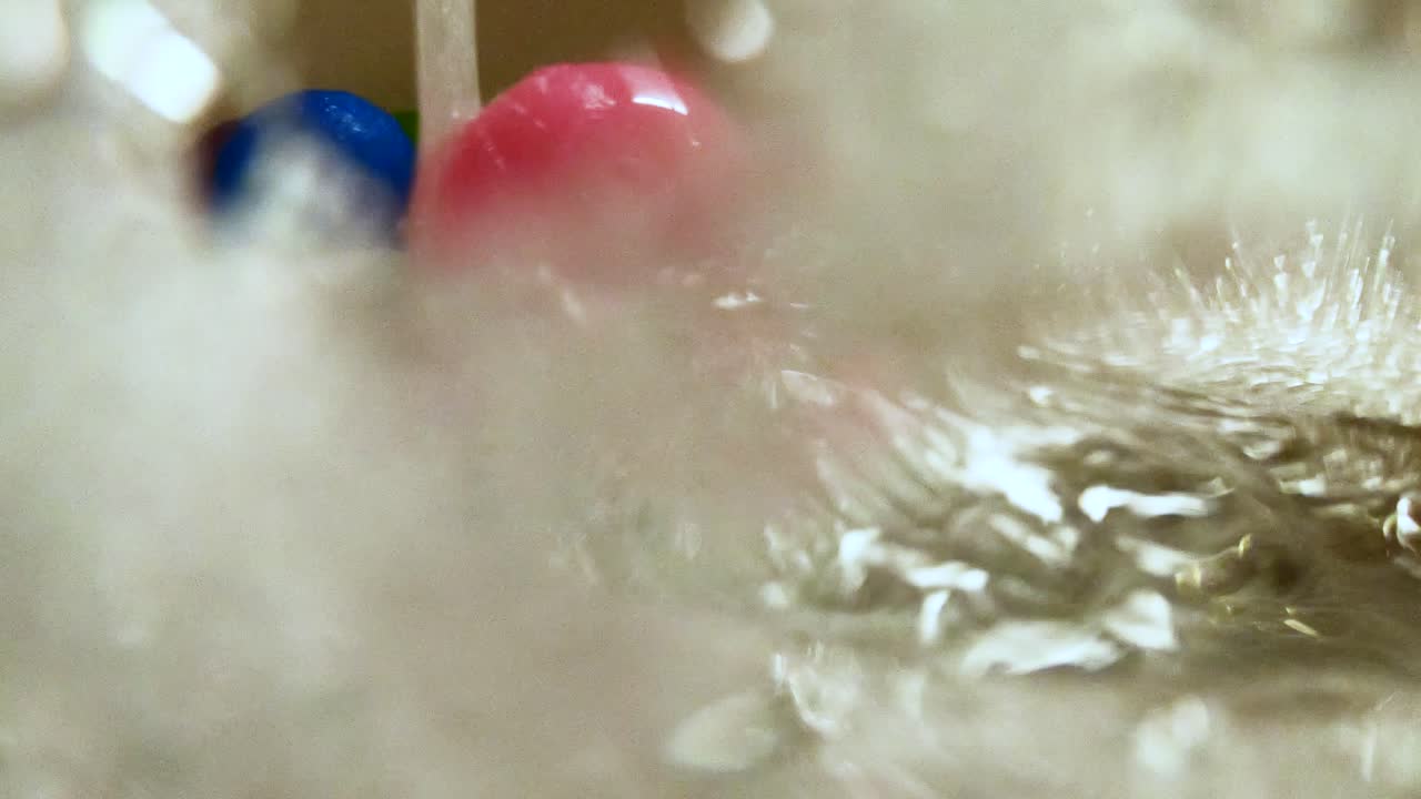 욕조에서 물 흐름에 의해 굴러가는 분홍색 플라스틱 공, 느린 동작, 화려한 집 장면, 어린이를 위한 편안한 거품 목욕, 어린 시절 개념