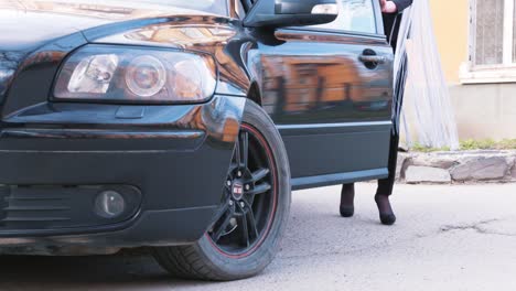 woman getting out of a black volvo car