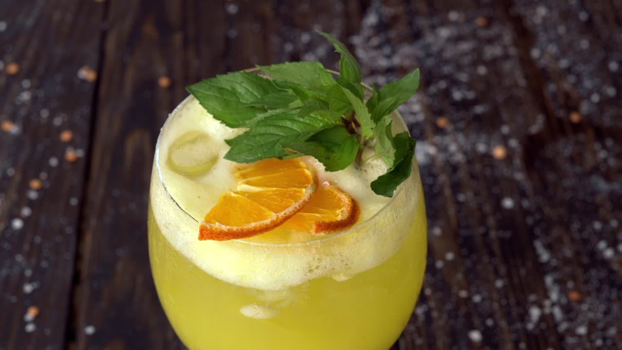 Et glas gul lemonade med mynte på en træoverflade