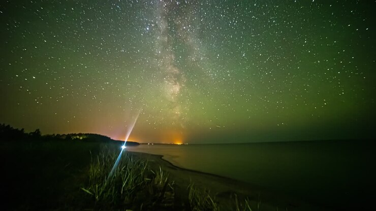 Il nucleo della Via Lattea attraversa il cielo notturno sull'Oceano Atlantico, poi l'aurora boreale tinge il cielo di verde - time lapse.