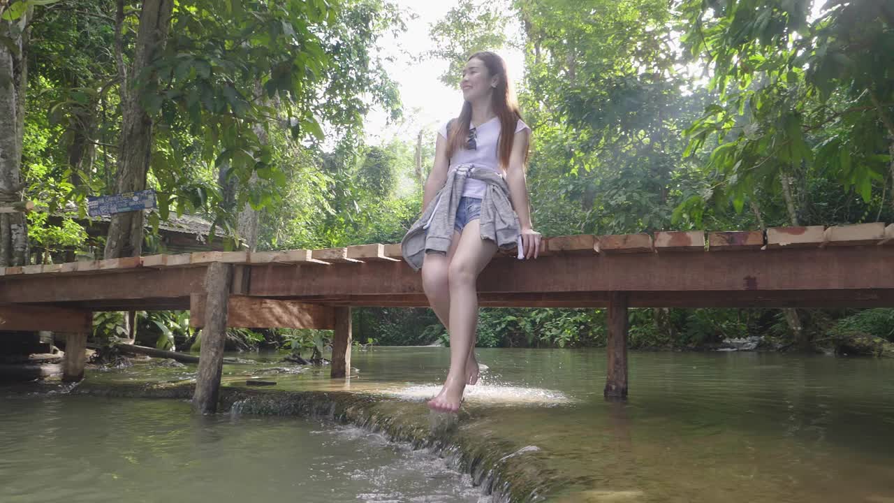 Asian Girl Sitting On Small Wooden Bridge And Relaxing With Water, Slow Motion