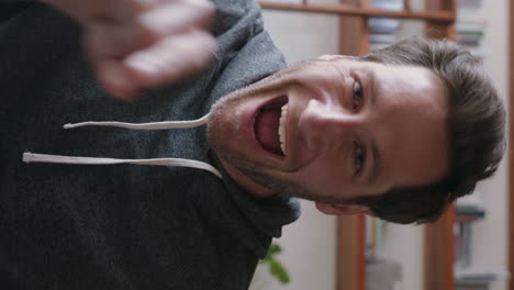 attractive-young-man-having-video-chat-using-webcam-at-home-waving-at-baby-sharing-lifestyle-father-enjoying-online-connection-on-vertical-screen