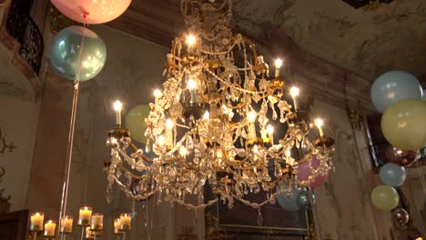 un enorme candelabro antiguo, rodeado de globos y velas, en un lugar atmosférico clásico para fiestas de bodas