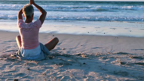 Ältere-Frau-Macht-Yoga-Am-Strand