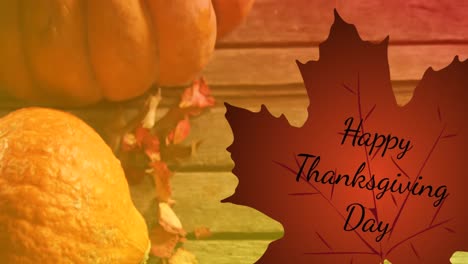 Animation-of-happy-thanksgiving-day-text-over-autumn-leaf-and-pumpkins-on-wooden-background