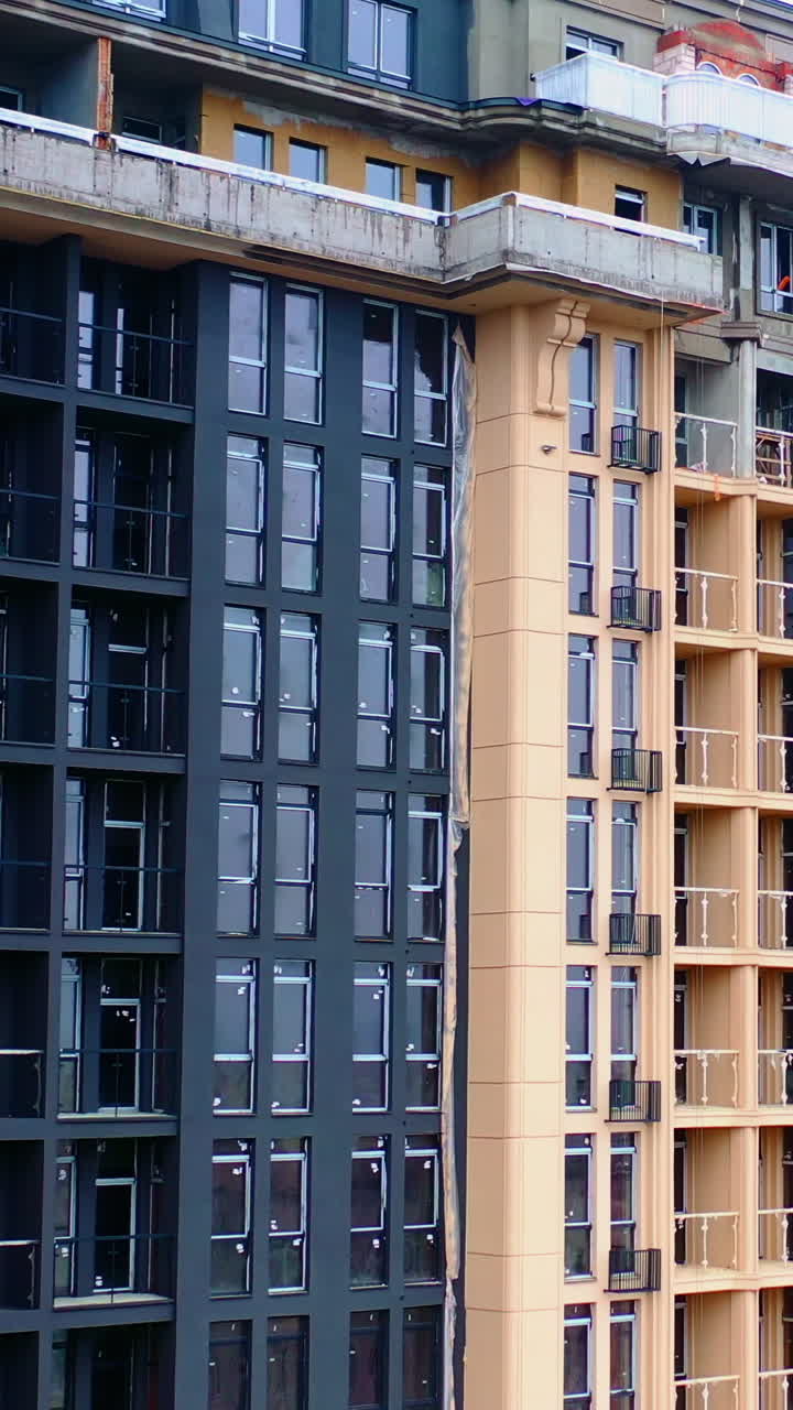 Construction of modern tower building. Exterior of a new architecture in the city. Building of high-rise house. Vertical video