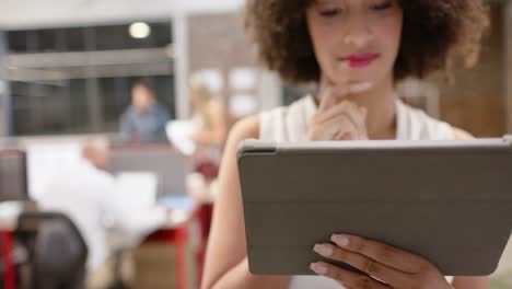 Portrait-of-happy-biracial-creative-businesswoman-using-tablet-in-casual-office,-in-slow-motion