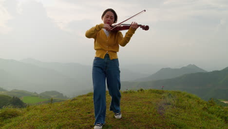 Friedliche-Geigenspielerin-Auf-Dem-Gipfel-Eines-Berges,-Wind-Im-Haar