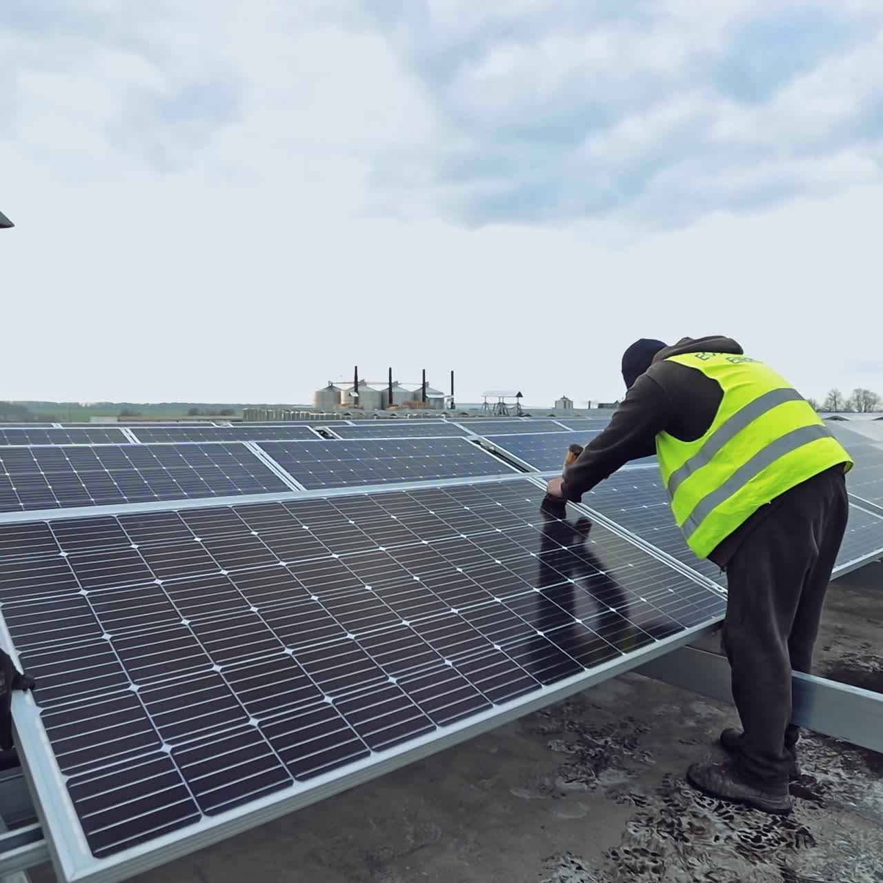 Workers attach photovoltaic panel. Construction of innovative solar energy farm on a flat roof of a huge building. Sustainable energy.