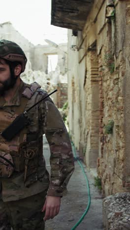 soldier looks for something among the ruins of the destroyed city by war