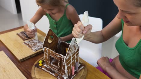 familia decorando una casa de pan de jengibre para navidad