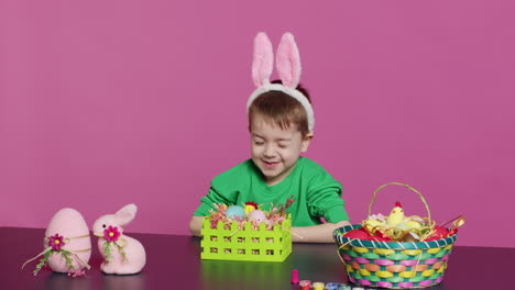 excited little kid decorating baskets with eggs and grass to prepare for easter