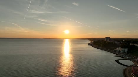 Der-Sonnenuntergang-Am-Southend-Pier-Steigt-Auf-Und-Sinkt-Dann.-Zeigt-Meereswellen-Und-Die-Küste-In-Der-Ferne,-Halbe-Silhouette