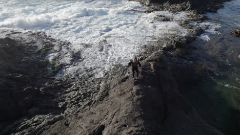 Fantastic-Aerial-shot-in-orbit-of-a-young-woman-who-is-among-the-natural-pools-and-where-the-waves-of-the-sea-can-be-seen