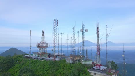 many cell towers on mountain top in indonesia, aerial drone orbit view