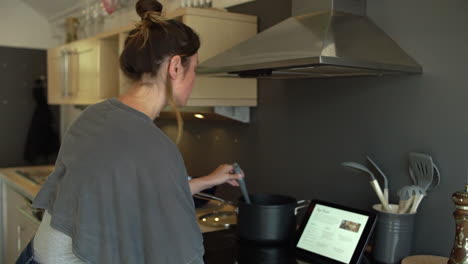 young woman stirring saucepan contents