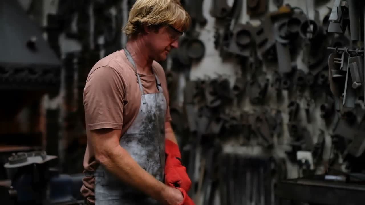 herrero usando guantes de mano en el taller 4k