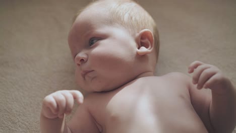 infant boy with large blue eyes and cheeks lies on table