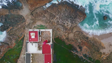 Top view red beacon on ocean cliffs. Coastal lighthouse placed on rocky seashore