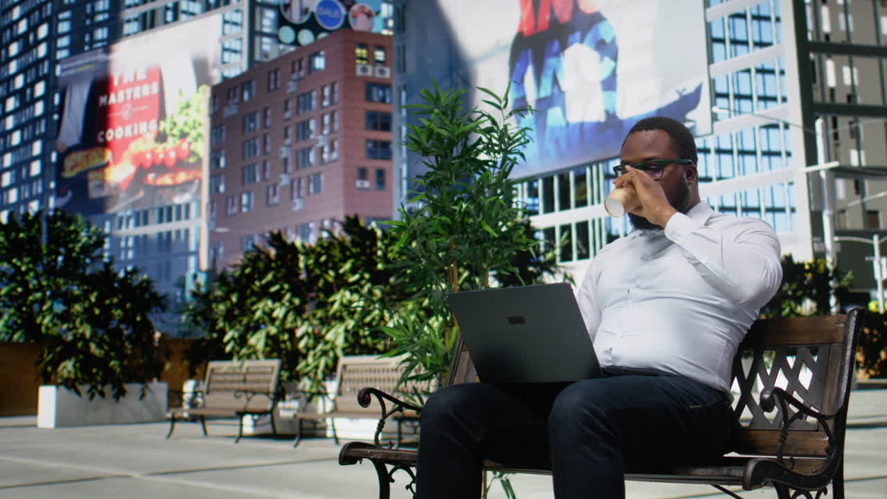 Adult man siting comfortably on a bench navigating a website on his laptop
