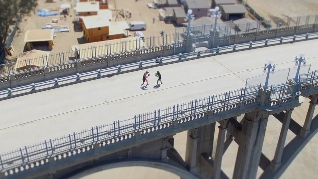 Slow push in drone shot of two men kickboxing on the Colorado Street Bridge, AKA Suicide Bridge, in Pasadena, California