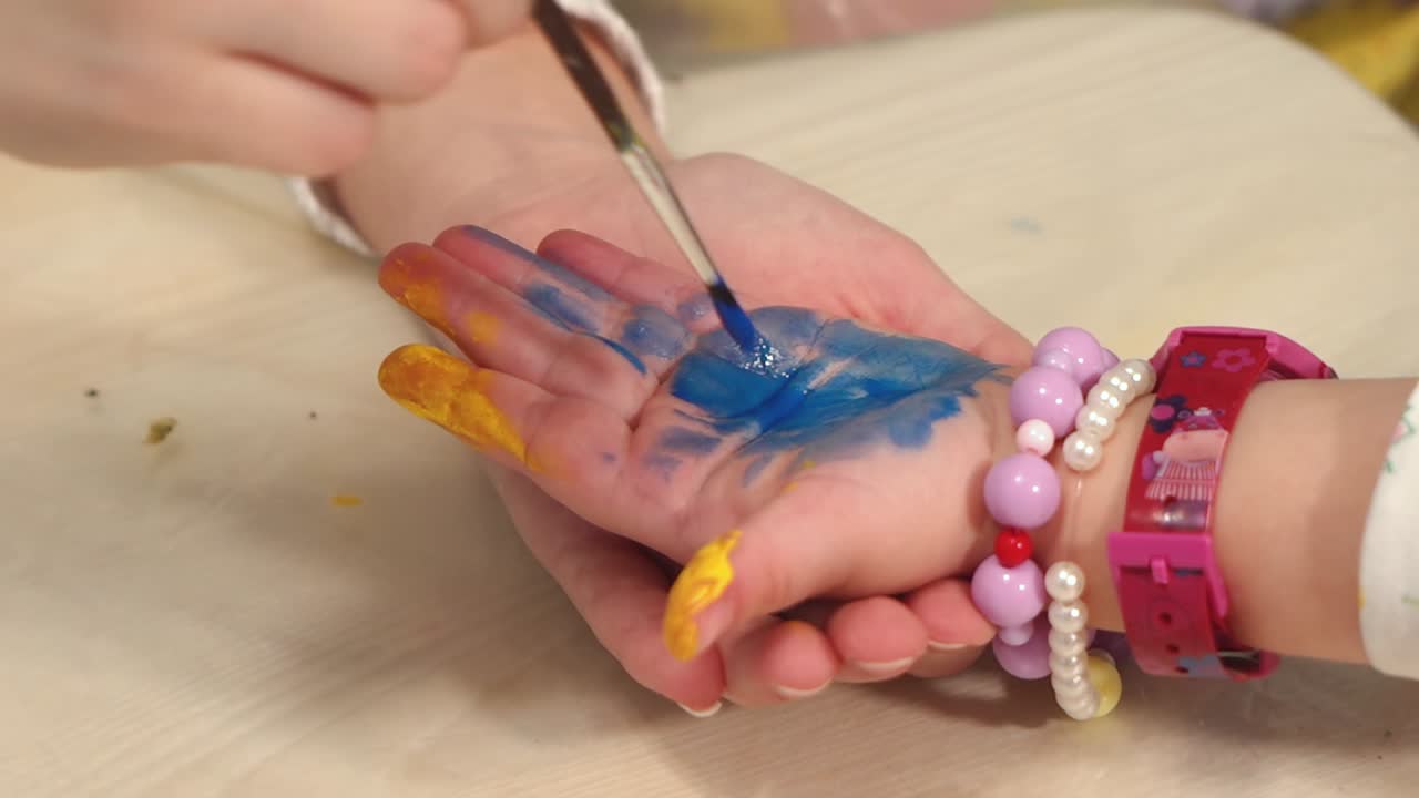 Funny child paints his hands with paint. Baby artist. Artist with dirty palms in paint.