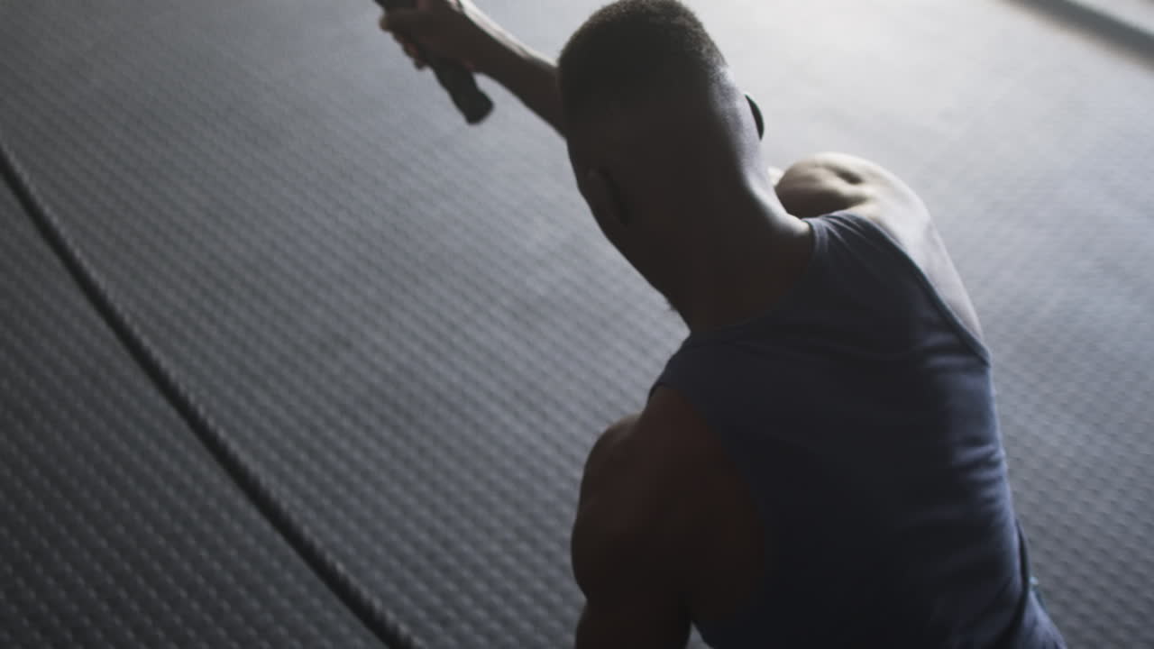 Using battle ropes, man exercising in gym for strength training workout