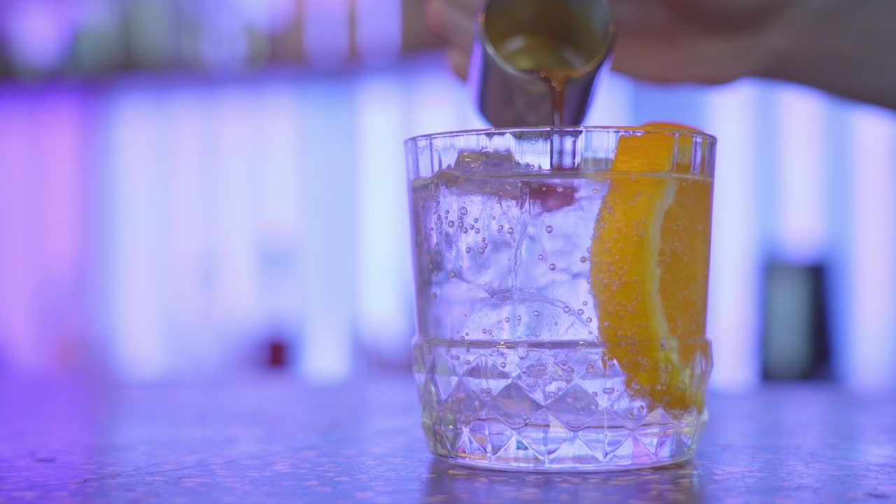 Bartender making espresso tonic by pouring espresso over ice and orange slices