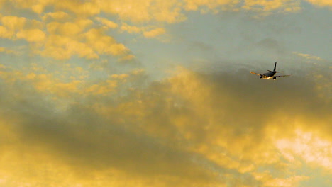 Beautiful-shot-of-airplane-flying-high-during-travel-in-golden-sunset-sky