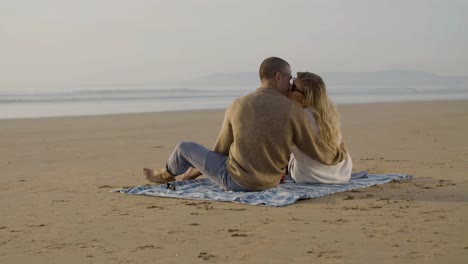 romantic caucasian couple having picnic on seashore at sunset.