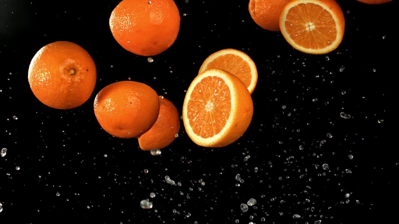 Al rallentatore di arance fresche e acqua che schizza su sfondo nero