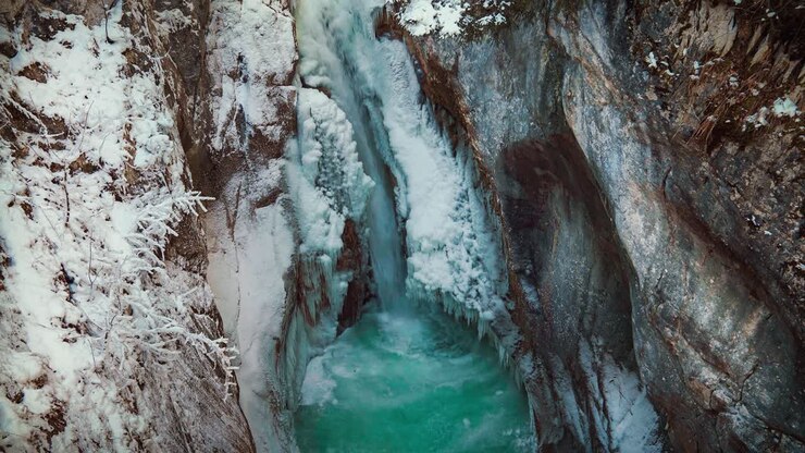 Cinemagraph / video in loop senza soluzione di continuità della famosa cascata Tatzlwurm e del canyon fluviale nelle Alpi bavaresi in inverno in Germania. L'acqua scorre impetuosa attraverso rocce naturali con neve e ghiaccio. 4K UHD